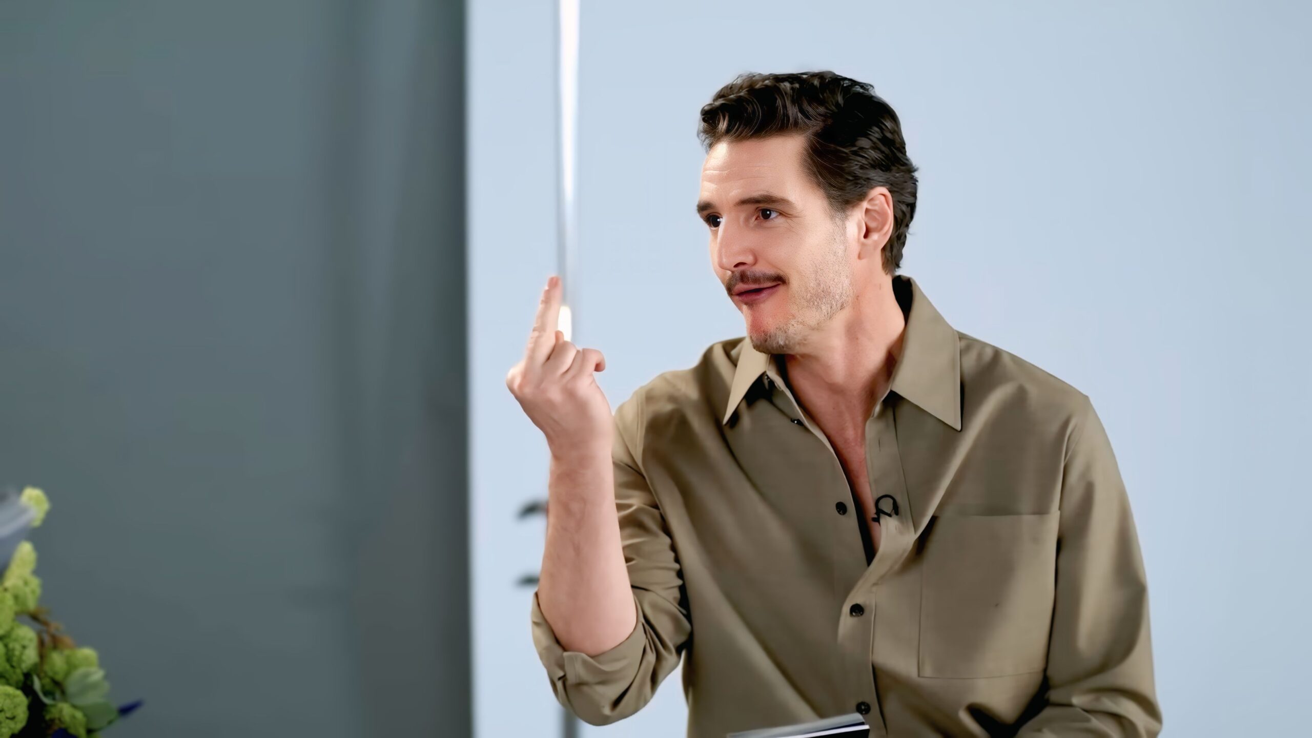 Pedro Pascal jokingly showing the middle finger while answering Dakota Johnson’s emoji question during their Vogue interview.