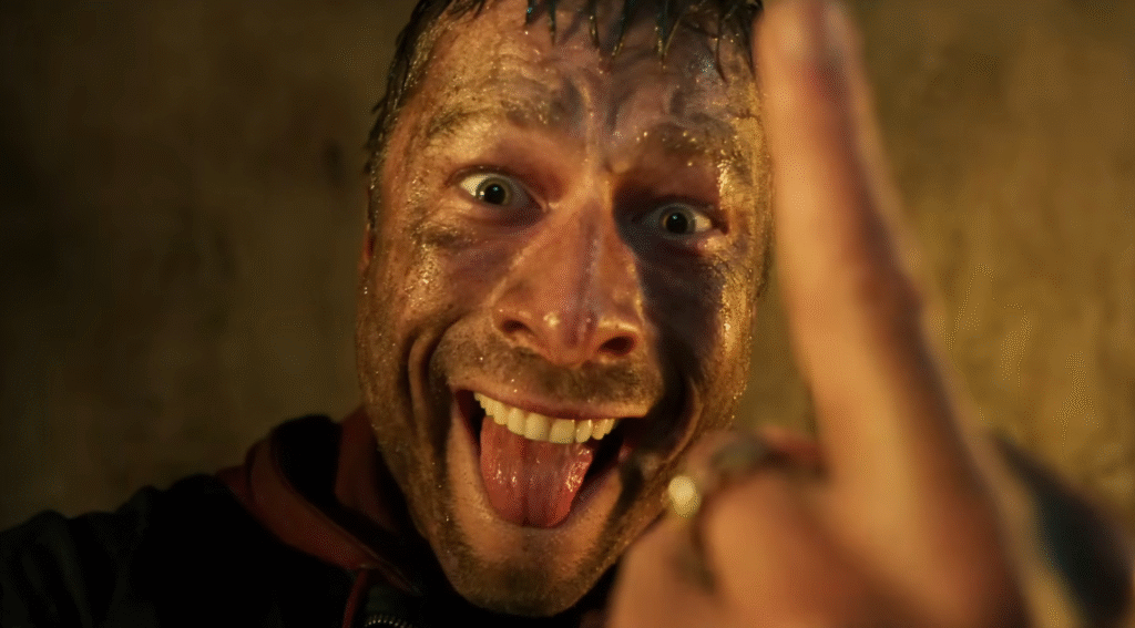 Glen Powell starring in The Running Man 2025 trailer, running through a dystopian game show arena